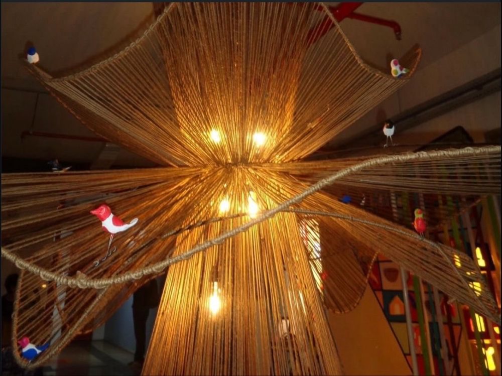 Luminária Opará, feita em sisal trançado, vista de baixo com pássaros de madeira nas bordas